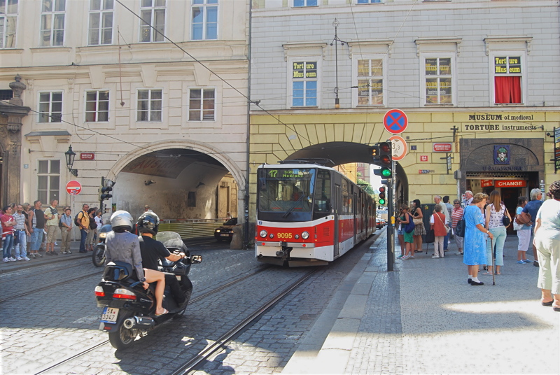 18 - A red-and-white tram navigating a narrow, historic street on Křižovnická street near the Charles Bridge in Prague